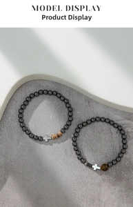 Detailed macro of hematite beaded bracelets with silver cross charms and tiger eye stone