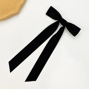 Detail of elegant black velvet bow hair clip with long ribbons on a white background