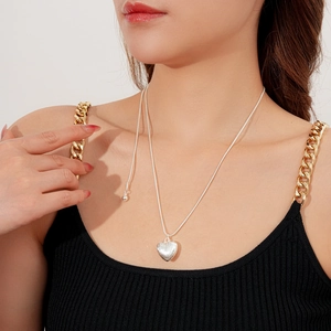 Détail d'un pendentif cœur en argent brossé sur une fine chaîne serpent pour femme