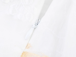 Dettaglio della cerniera invisibile su abito jacquard bianco con strisce dorate eleganti