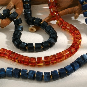 Gros plan sur un collier en perles de résine ambre et bleu marbré avec détails dorés
