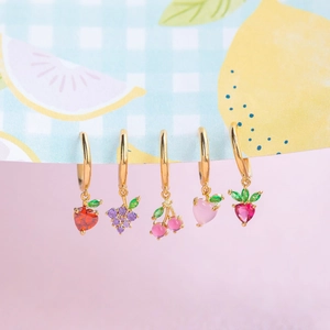 Macro view of gold hoop earrings with colorful zircon strawberry and cherry fruit charms