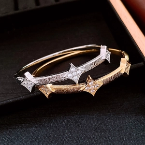 Macro detail of gold and silver star bangles with brushed texture on black velvet