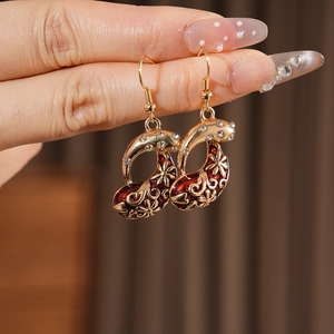 Close-up of red enamel flower earrings with gold finish and sparkling rhinestones