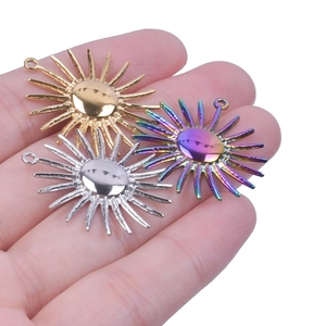 Three stainless steel sun pendants in gold, silver, and rainbow colors held in hand