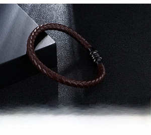 Detail of dark brown braided leather bracelet with black metallic spiral screw clasp