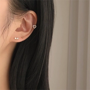 Close-up of golden bow earrings and heart ear cuff set with sparkling zircons on model