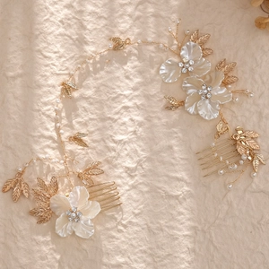 Elegant gold bridal hair comb set with white flowers, pearls and leaves on beige background