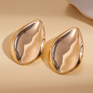 Close-up of golden teardrop earrings with a high-polished mirror metallic finish