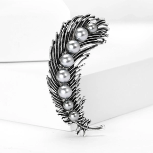 Macro view of vintage silver feather brooch with elegant grey pearls on metallic finish