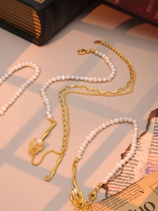 Detail of baroque freshwater pearl necklace with irregular gold pendants on vintage paper