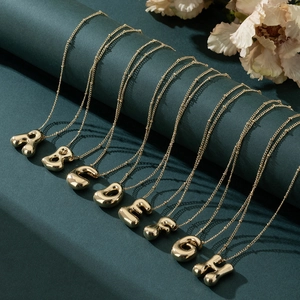 3D gold balloon letter pendant necklaces with bead chains on luxury green display