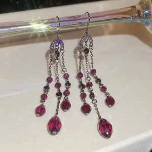 Détail de boucles d'oreilles pampilles en argent foncé avec cristaux fuchsia et lune