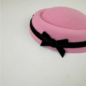 Detailed close-up of the pink pillbox hat with a soft velvet finish and black bow accent