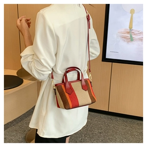 Detail of red and beige striped woven tote bag worn as a stylish crossbody bag
