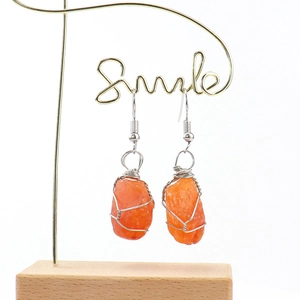 Handmade silver wire wrapped orange raw stone crystal earrings for women on display