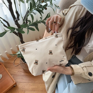 Detail of cute bear pattern corduroy cosmetic bag held in a cozy home setting