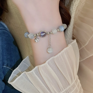 Detail of beaded bracelet featuring blue opals, purple gemstone and star charm pendant
