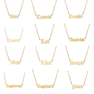 Set di 12 collane zodiacali dorate con pendenti in carattere gotico su sfondo bianco