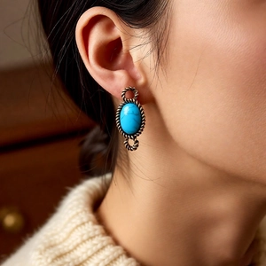 Detail shot of vintage bronze-tone twisted rope earrings with oval turquoise resin stones