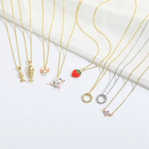 Close-up of minimalist gold and silver necklaces with animal and strawberry charms