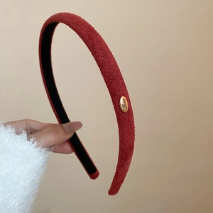 Détail d'un serre-tête en velours bordeaux avec plaque dorée Love et doublure antidérapante