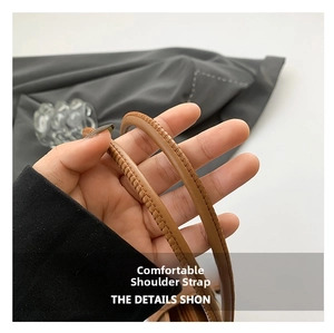 Close-up of a brown leather shoulder strap featuring fine stitching and smooth texture