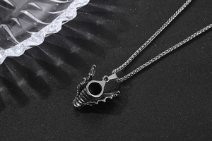 Gros plan du pendentif dragon noir avec cylindre creux sur une chaîne en acier inox