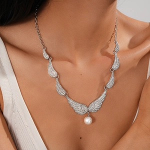 Close-up of sparkling winged angel pendant with round white pearl on elegant neck chain