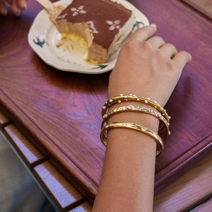 Detailed view of three gold-plated stainless steel bracelets with pearls and zircons