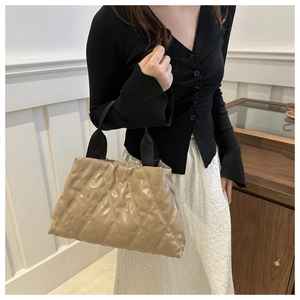 Detail of beige quilted handbag with soft texture and stylish black carry handle