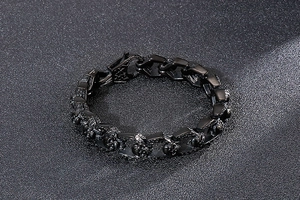Close-up of a polished black titanium steel skull bracelet in a gothic punk style