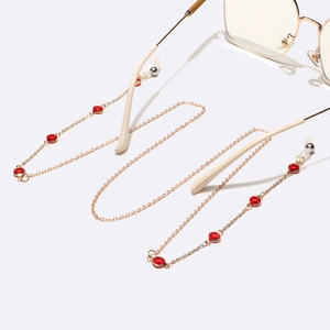Detail view of a gold glasses chain with red crystal beads and transparent silicone loops