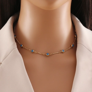 Close-up of a double-layered gold stainless steel necklace with blue evil eye beads on a model