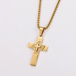 Macro shot of gold stainless steel cross pendant with intricate geometric carvings