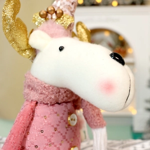 Close-up of pink reindeer plush toy with sequin hat, golden antlers and soft velvet neck wrap