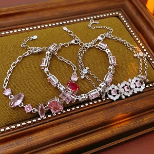 Detailed close-up of vintage silver bracelets with zircon gems on a green velvet base