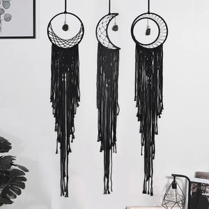 Detailed trio of black woven dreamcatchers with tassels and stones on home wall
