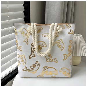 Close-up of a white canvas tote bag with golden dolphin print and cotton rope handles