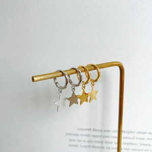 Detail view of gold and silver S925 sterling silver star drop earrings on a stand