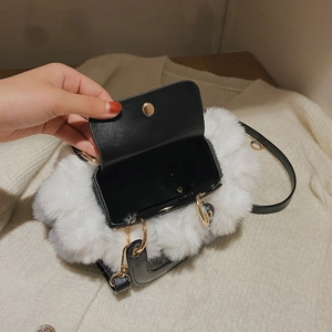 Top view of plush black and white faux fur handbag with gold snap button and leather interior