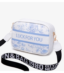 Detail of white camera bag with blue floral print and wide striped crossbody strap