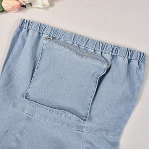 Dettaglio dell'abito in denim azzurro con vita elastica e una grande tasca con cerniera