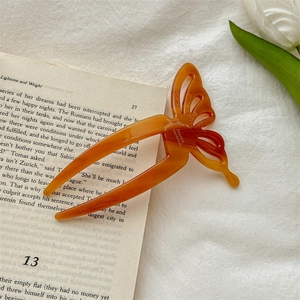 Detail of amber butterfly hair pin made of acetate on a book with white tulip decoration