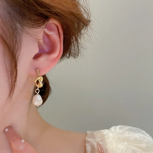 Gros plan de boucles d'oreilles nœud élégantes avec perle baroque sur l'oreille