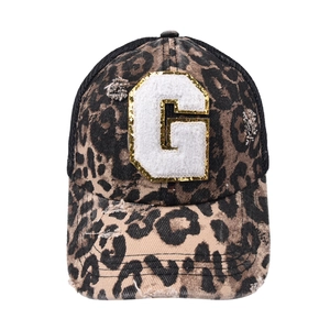 Detailed close-up of leopard print trucker hat with gold-edged sequined letter G patch