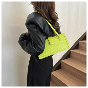 Dettaglio della borsa baguette verde neon stampa coccodrillo con giacca di pelle nera