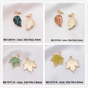 Detailed size view of enamel maple leaf charms in peacock blue and coral orange