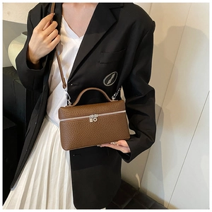 Brown lychee pattern leather box bag held by model in black blazer and white skirt