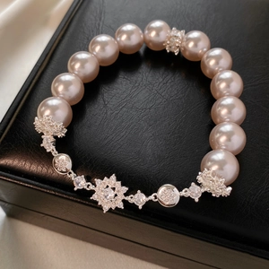 Détail du bracelet perles champagne avec breloques flocon en zircon sur cuir noir